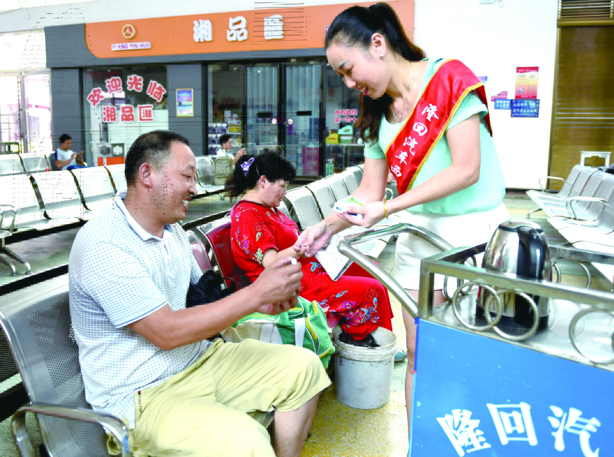 隆回分公司汽車西站工作人員正在為旅客免費(fèi)贈(zèng)送藿香正氣水。